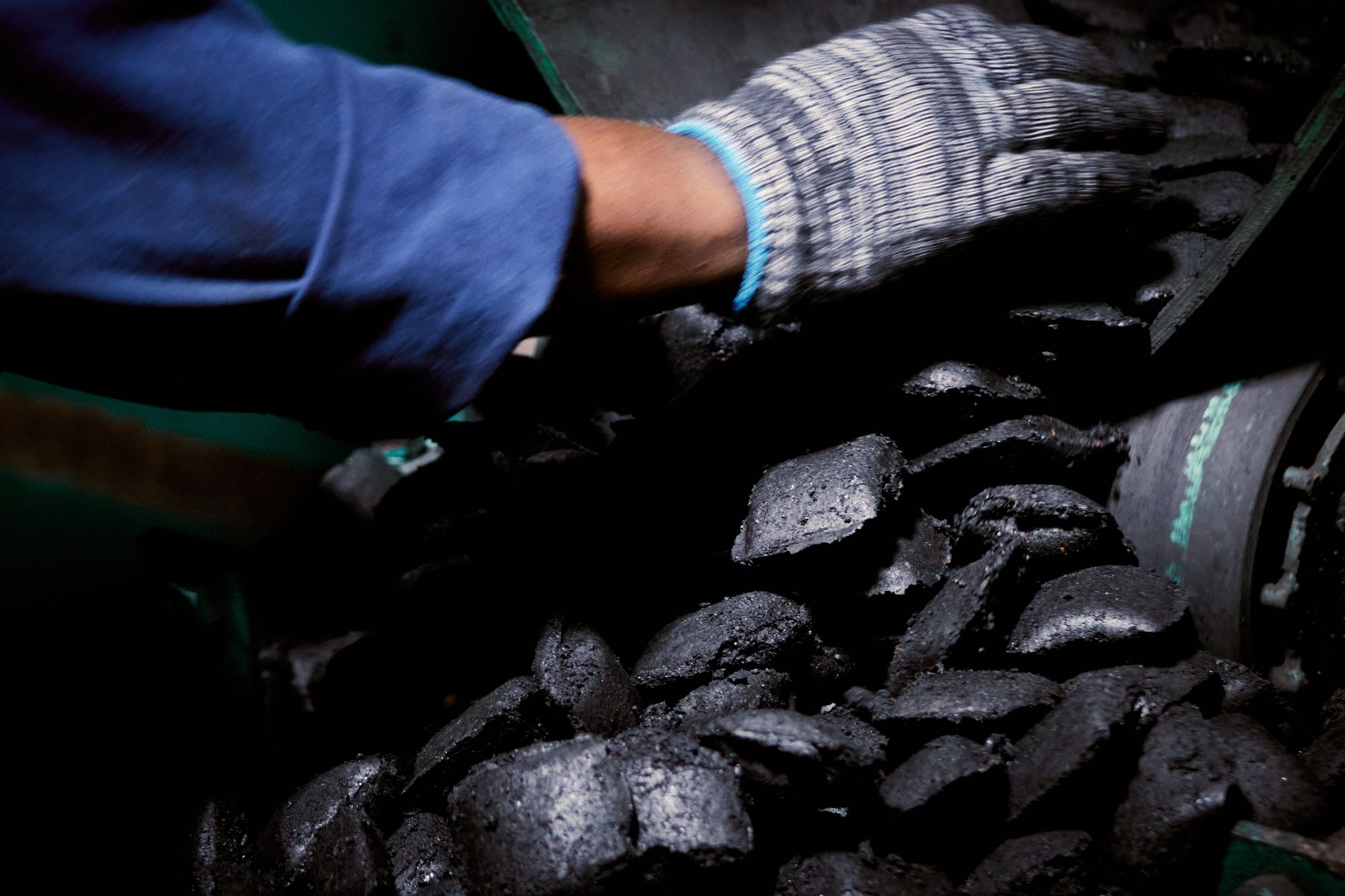 A gloved hand among freshly pressed char-briquettes